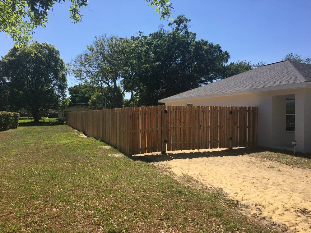 A wooden fence is in the backyard of a house.