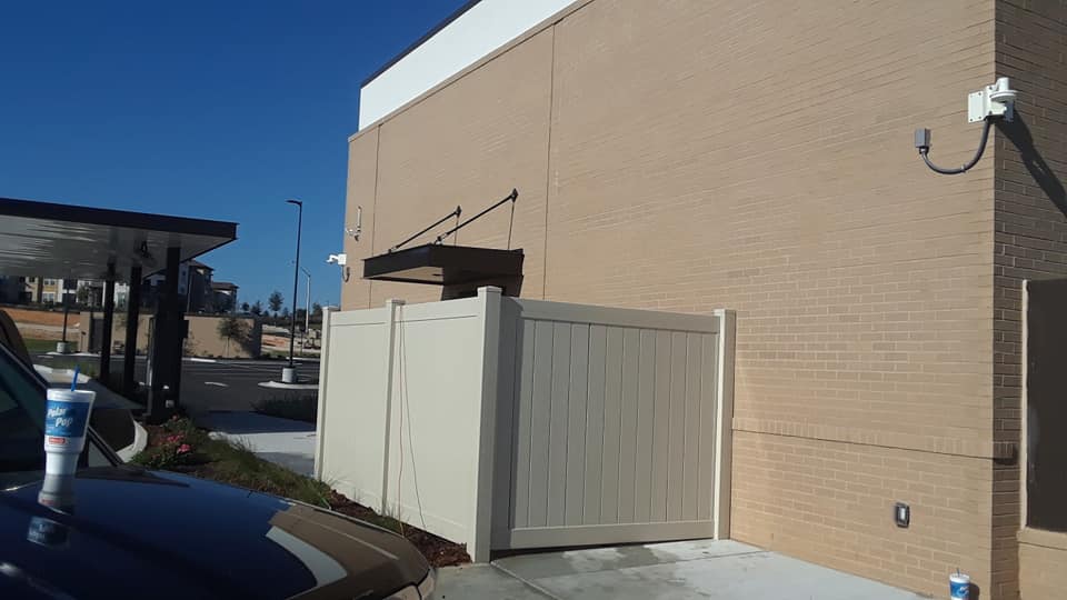 A car is parked in front of a building with a white fence.