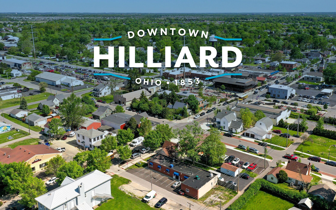 Aerial view of downtown Hilliard, Ohio with buildings, trees, and cars. Green and blue colors. Aerial view of downtown Hilliard, Ohio with buildings, trees, and cars. Green and blue colors.