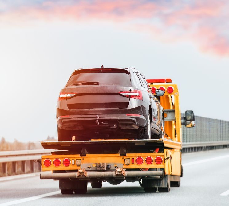 A car is being towed by a tow truck on a highway.