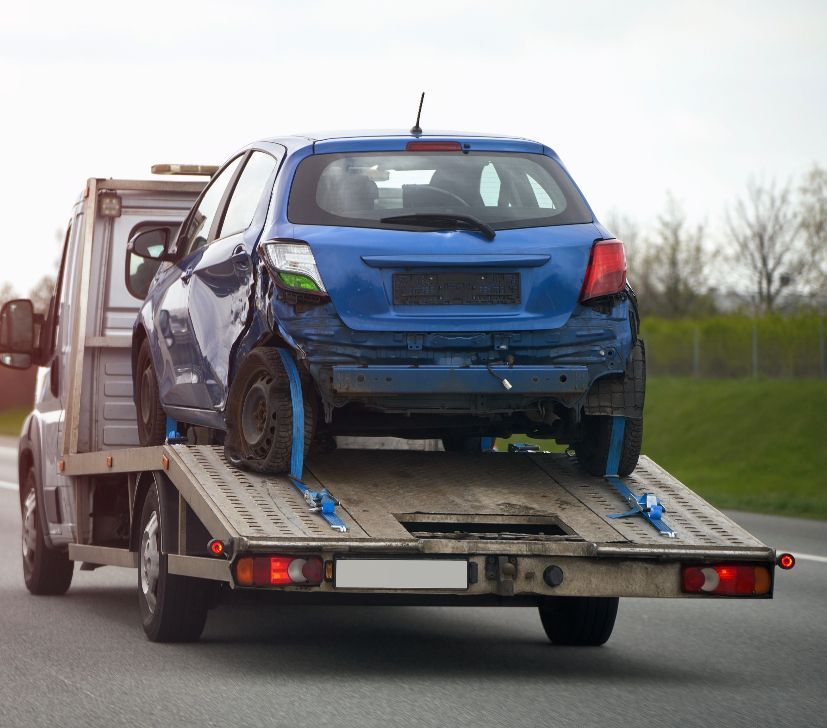A blue car is being towed by a tow truck.