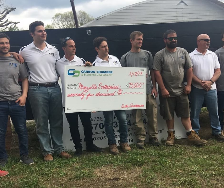 A group of men standing next to each other holding a large check.