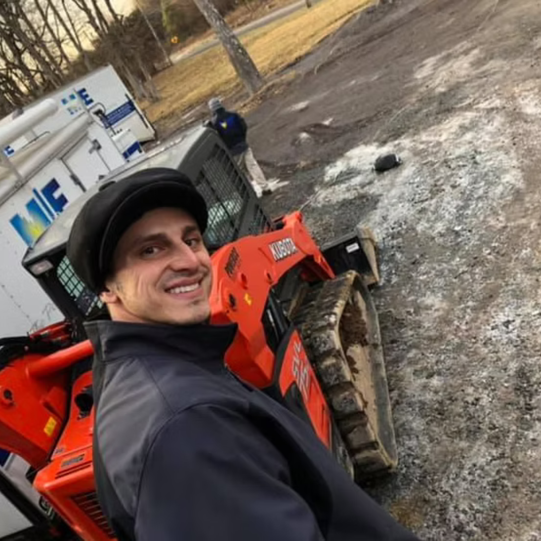 A man is standing in front of an orange tractor and a white truck that says ' dale ' on it