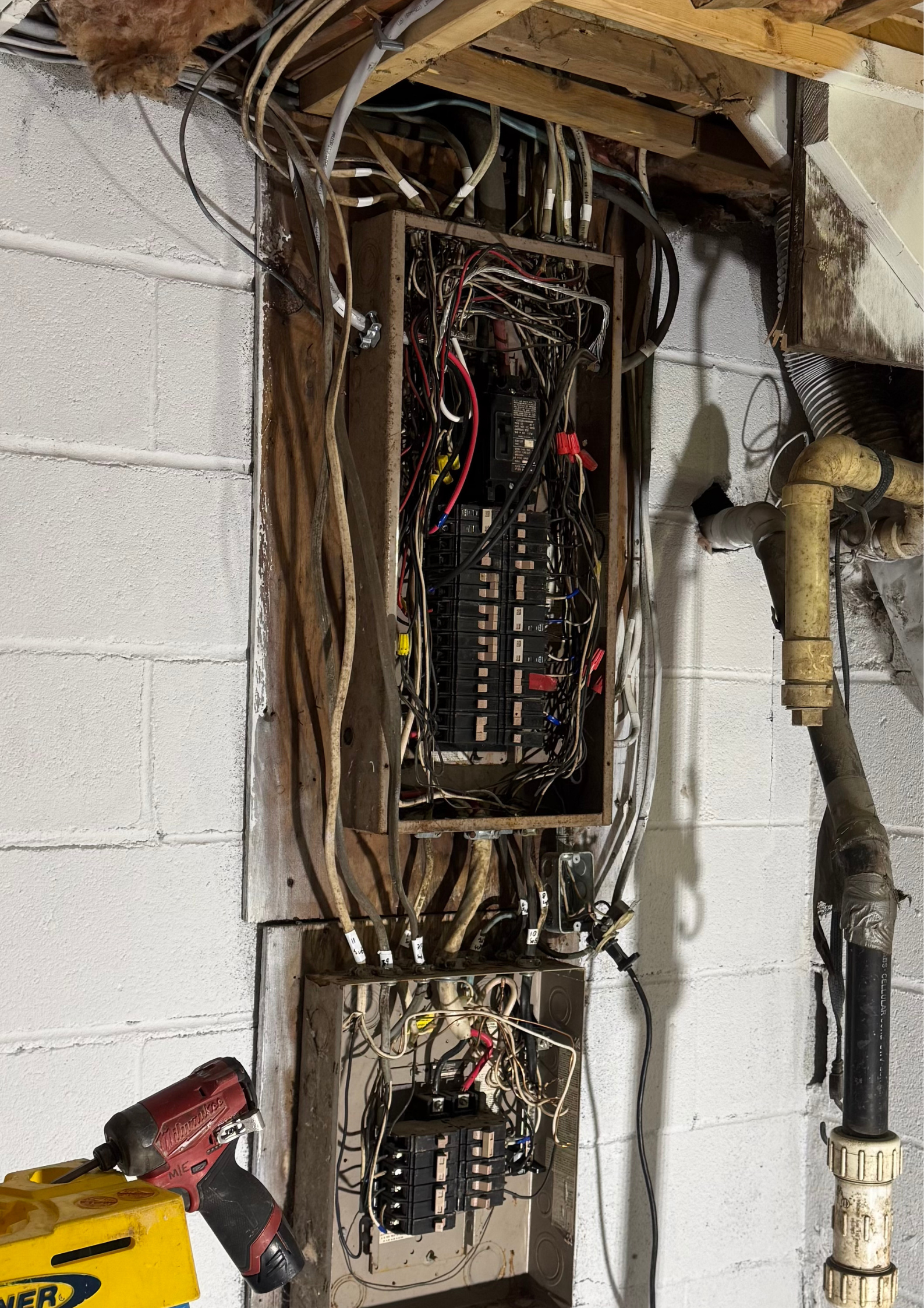 A broken electrical box is sitting on a brick wall.