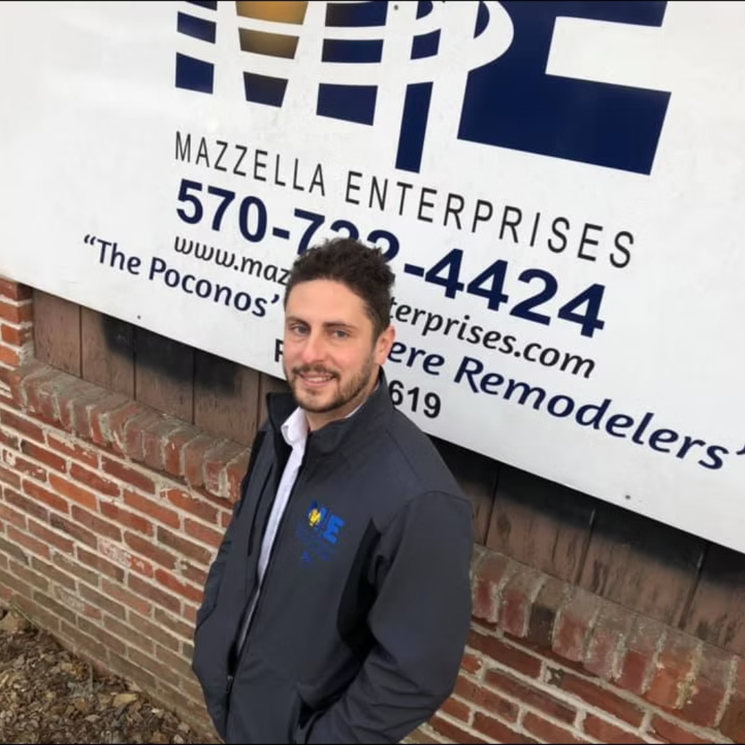 A man standing in front of a mazzella enterprises sign