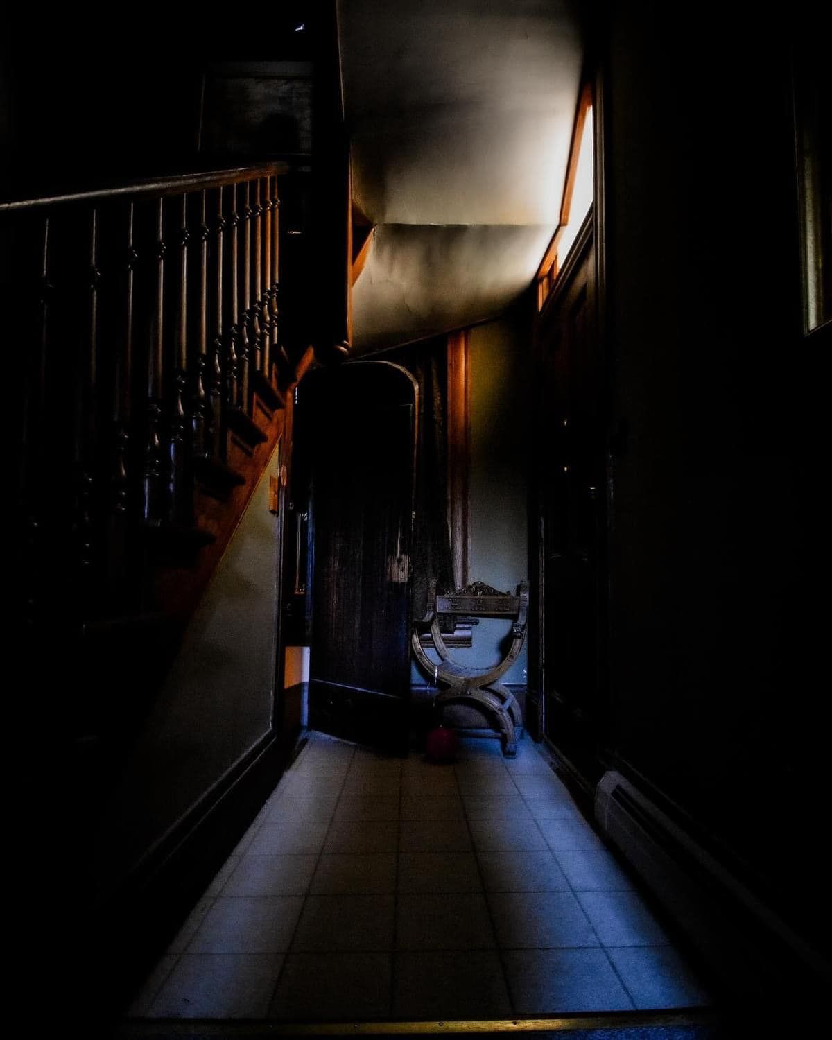 A dark hallway with stairs and a chair in the corner