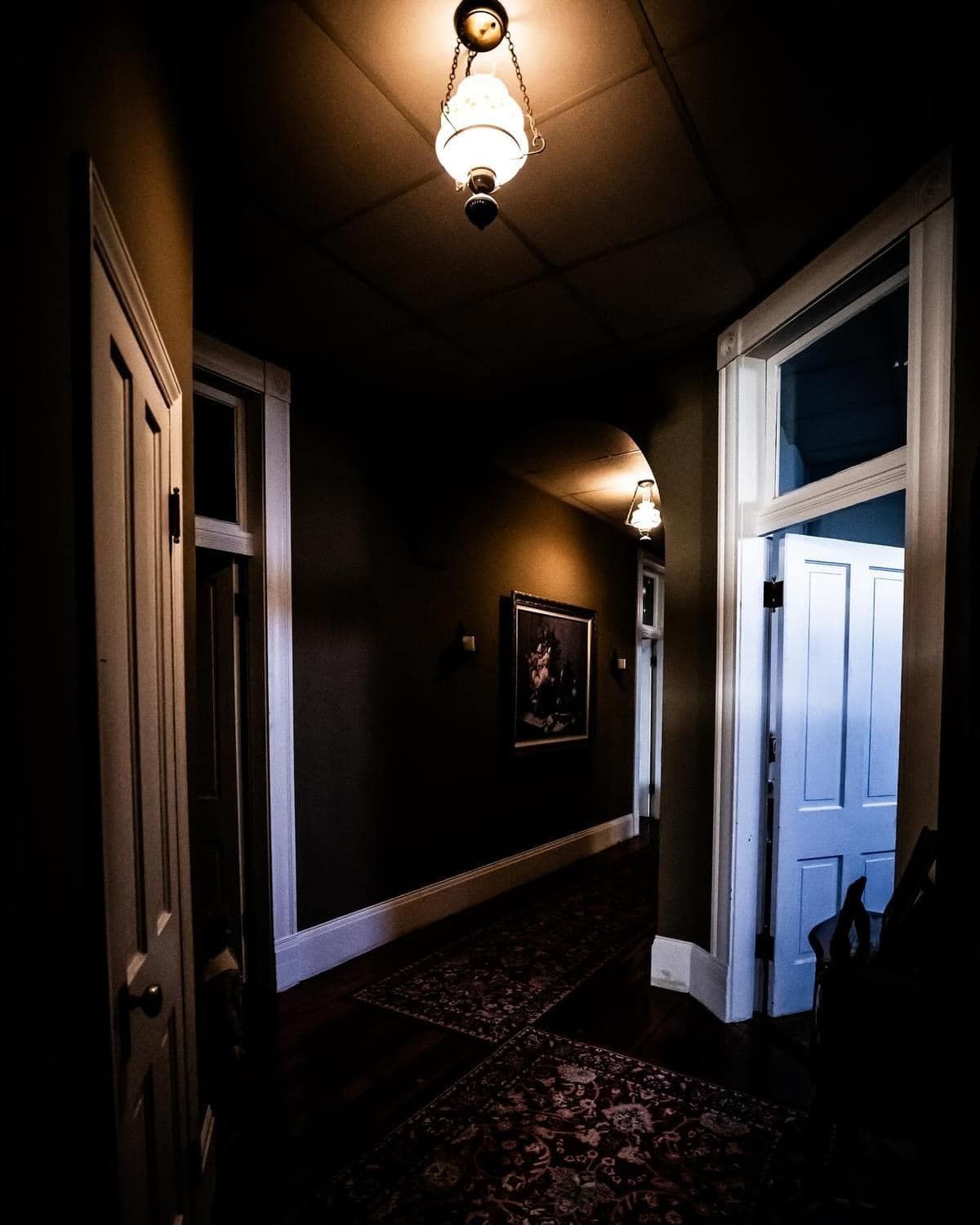 A dark hallway with a lamp hanging from the ceiling