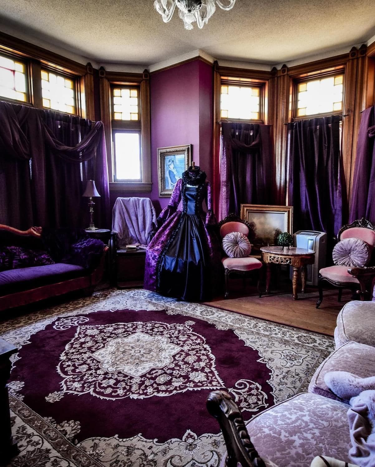 A woman in a black dress is standing in a living room with purple walls