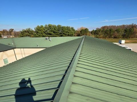 A green roof of a building with a blue sky in the background.