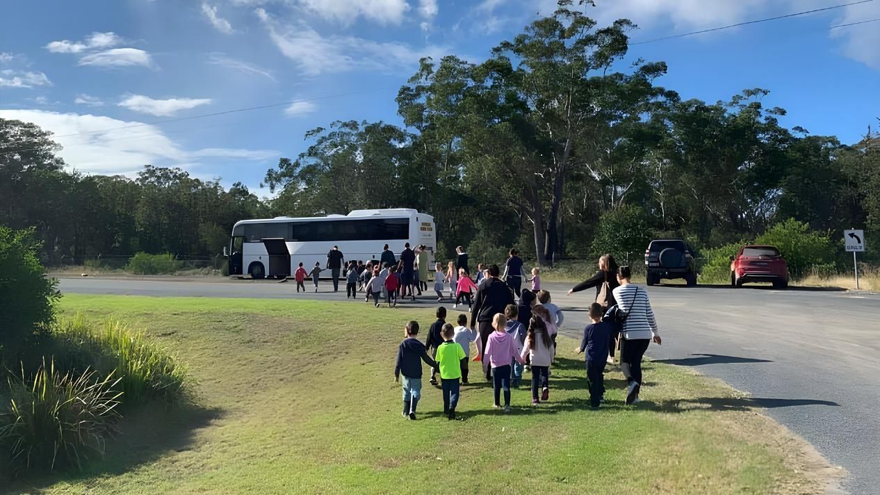 A Group Of Children Are Walking Down A Grassy Path Next To A Bus — Kiddies Hut @ Diamond Beach In Diamond Beach, NSW