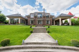 Luxurious brick house with a well-manicured lawn and stone pathway leading to the entrance.