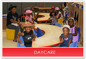 Daycare children wearing hats, sitting at tables with a teacher.