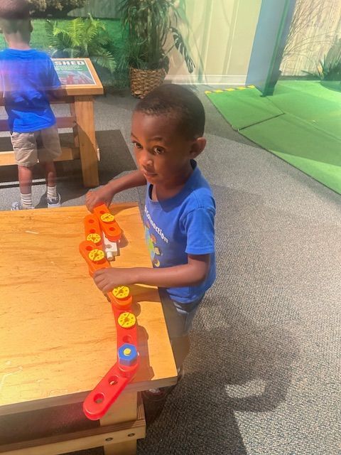 Boy in blue shirt playing with colorful building blocks at a table.