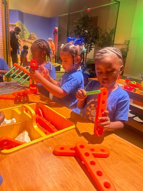 Teacher reading to a group of children in a classroom with colorful decorations and toys.