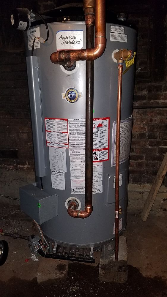 A water heater is sitting in a basement next to a brick wall in Chicago.