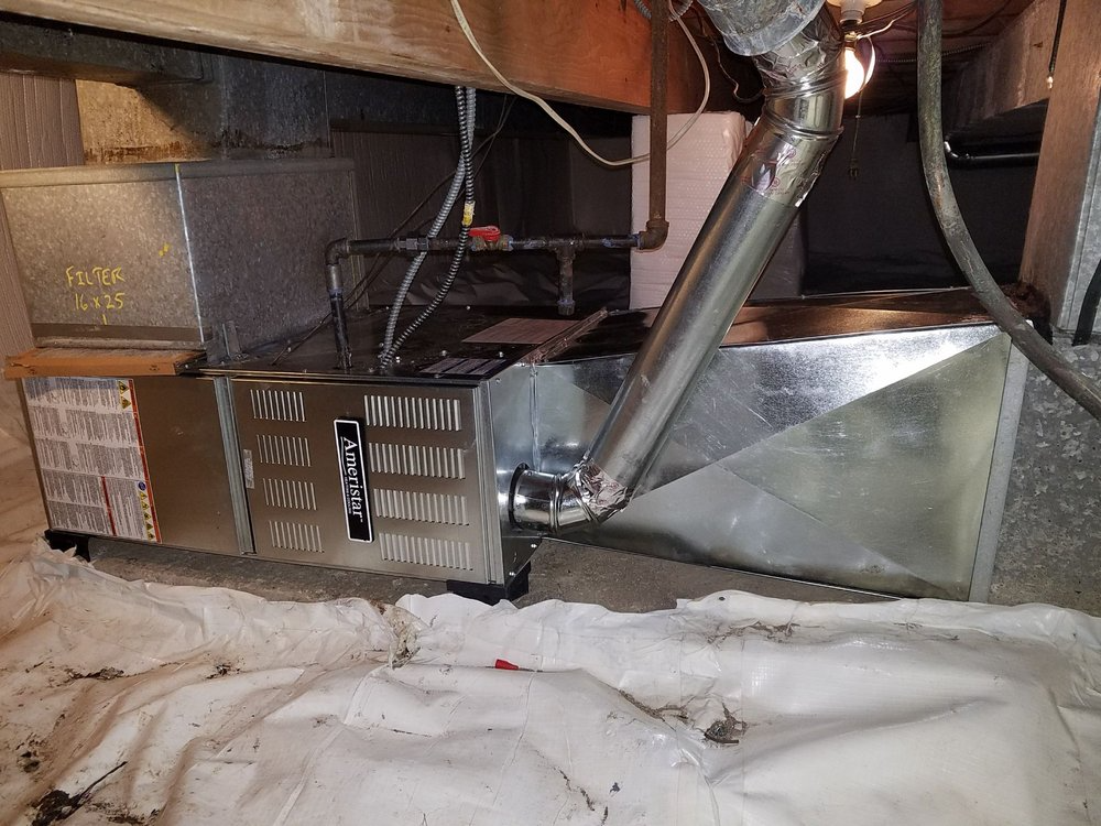 A furnace is sitting under a ceiling in a basement in Chicago.