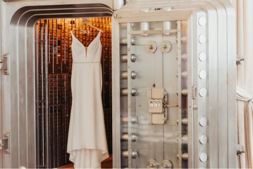 A wedding dress hangs inside an open bank vault.