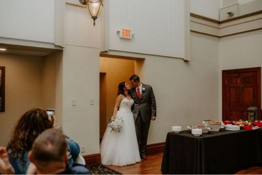 Bride and groom kissing in doorway after ceremony; guests watch, snacks on table.