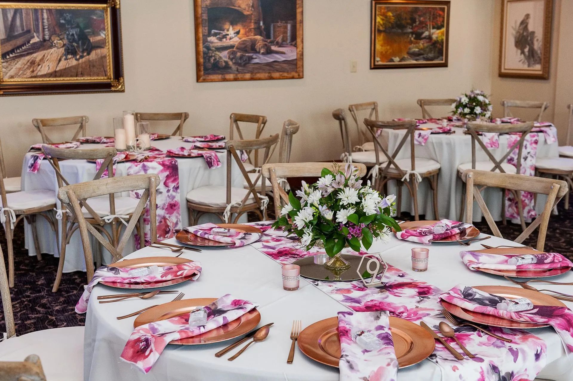 Wedding reception tables with floral centerpieces, white tablecloths, and wooden chairs.
