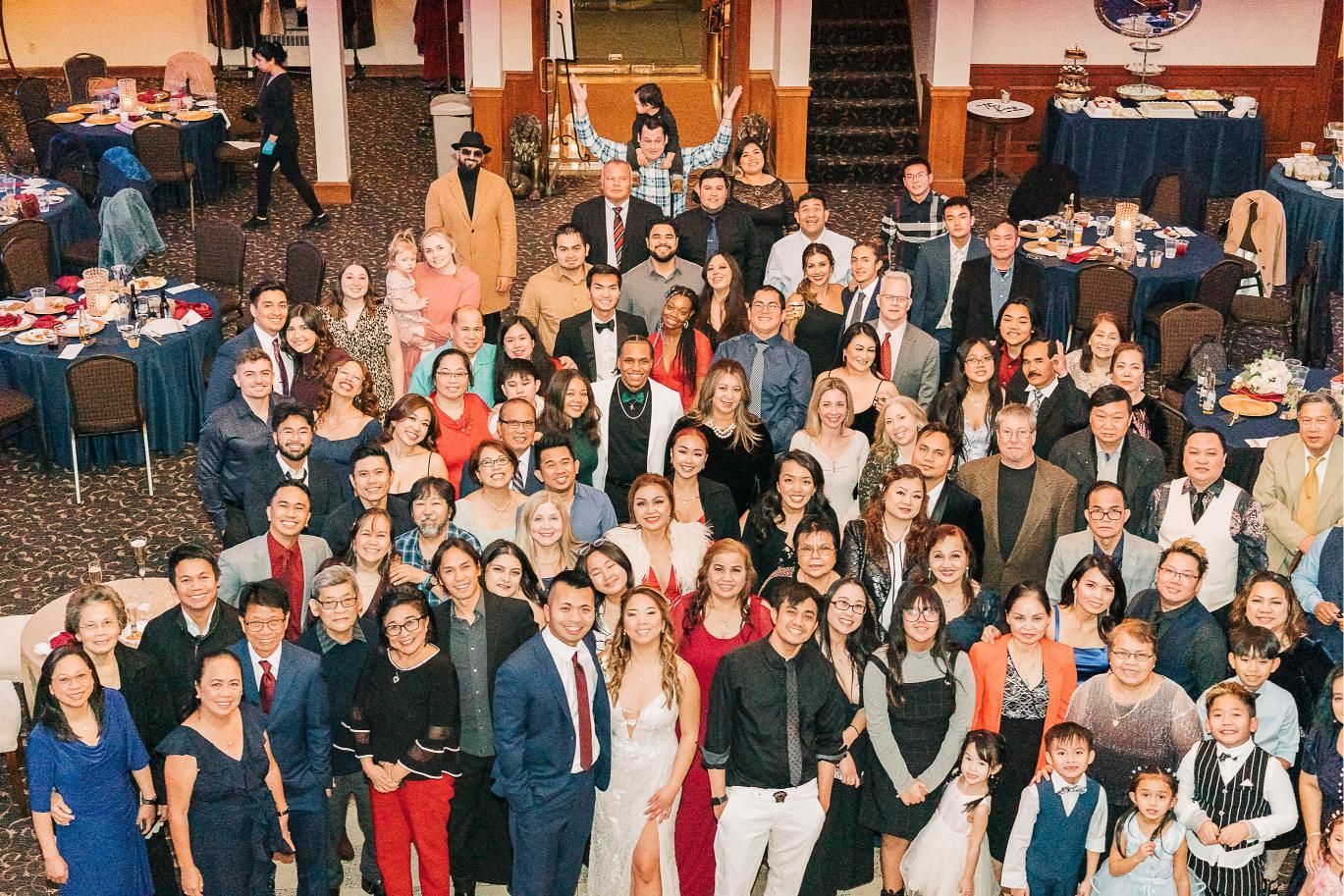 Large group of people, formal attire, at a celebratory event in a decorated banquet hall.