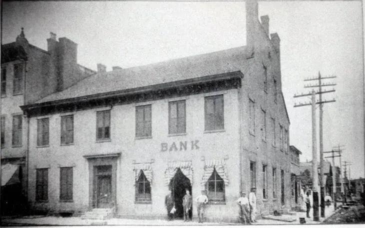 Black and white photo of a two-story brick bank building with the word 