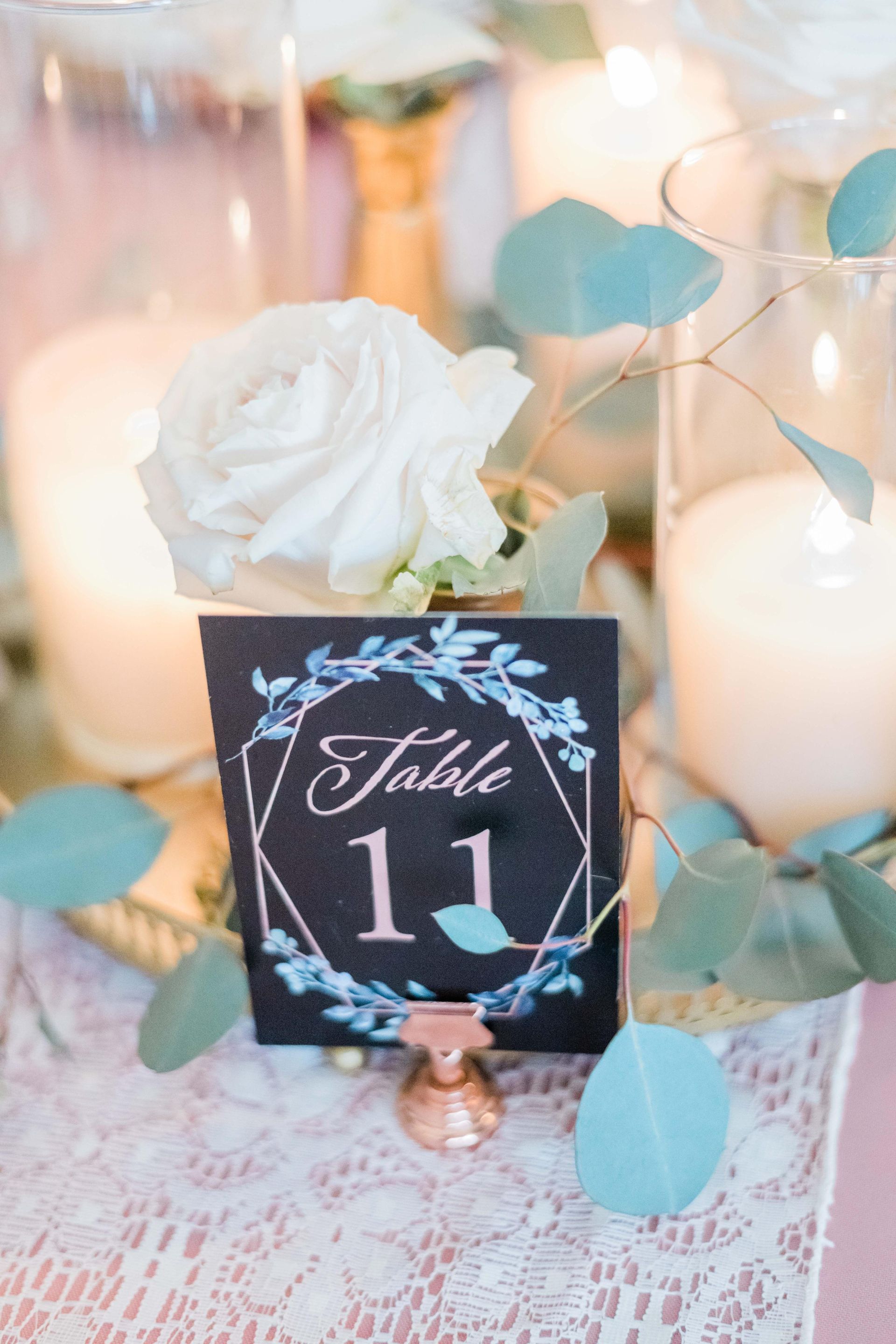 Table number 11 at a wedding reception. Black card with floral design and rose clip.