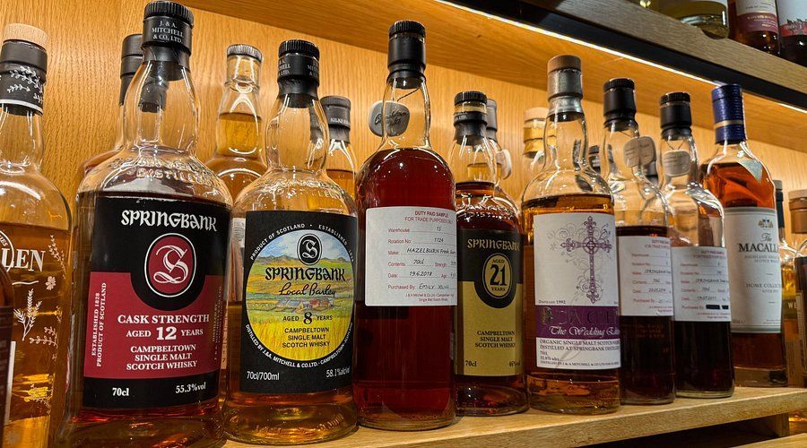 Row of various liquor bottles on a bar, including vodka, rum, and whiskey; indoor setting.