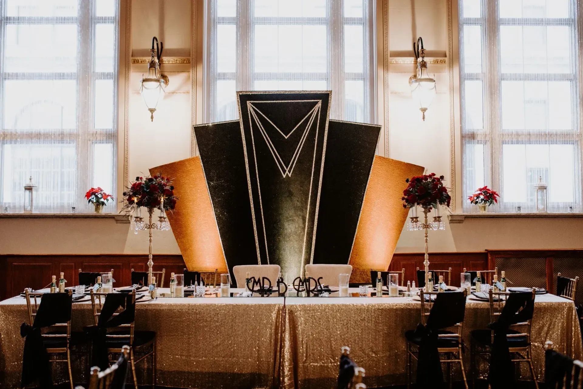 A glamorous wedding reception with gold and black Art Deco-style backdrop. 