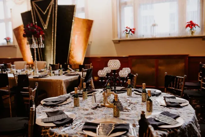 A banquet hall with art deco decor: round tables set with gold accents and black napkins