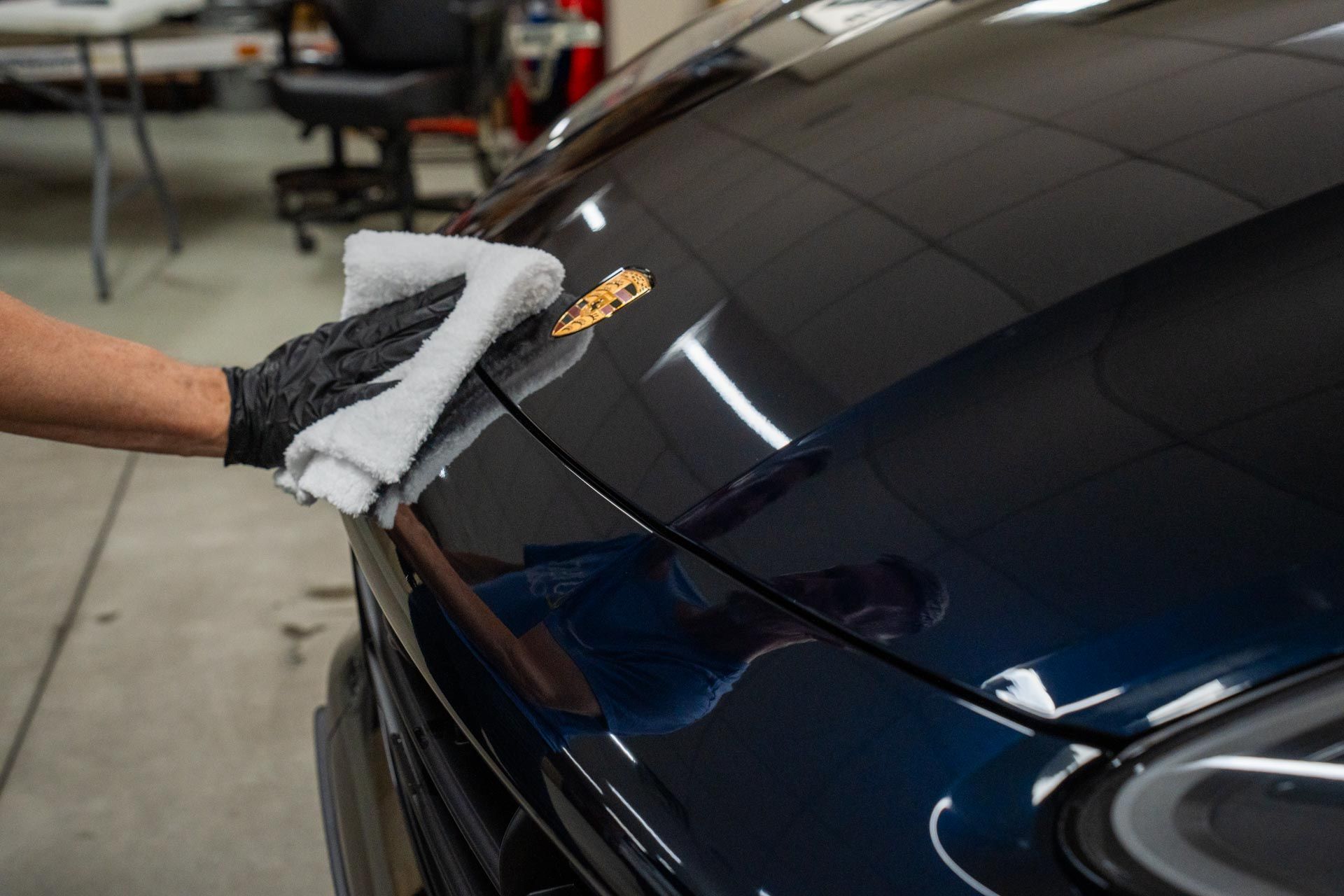 A person is cleaning the hood of a car with a towel.