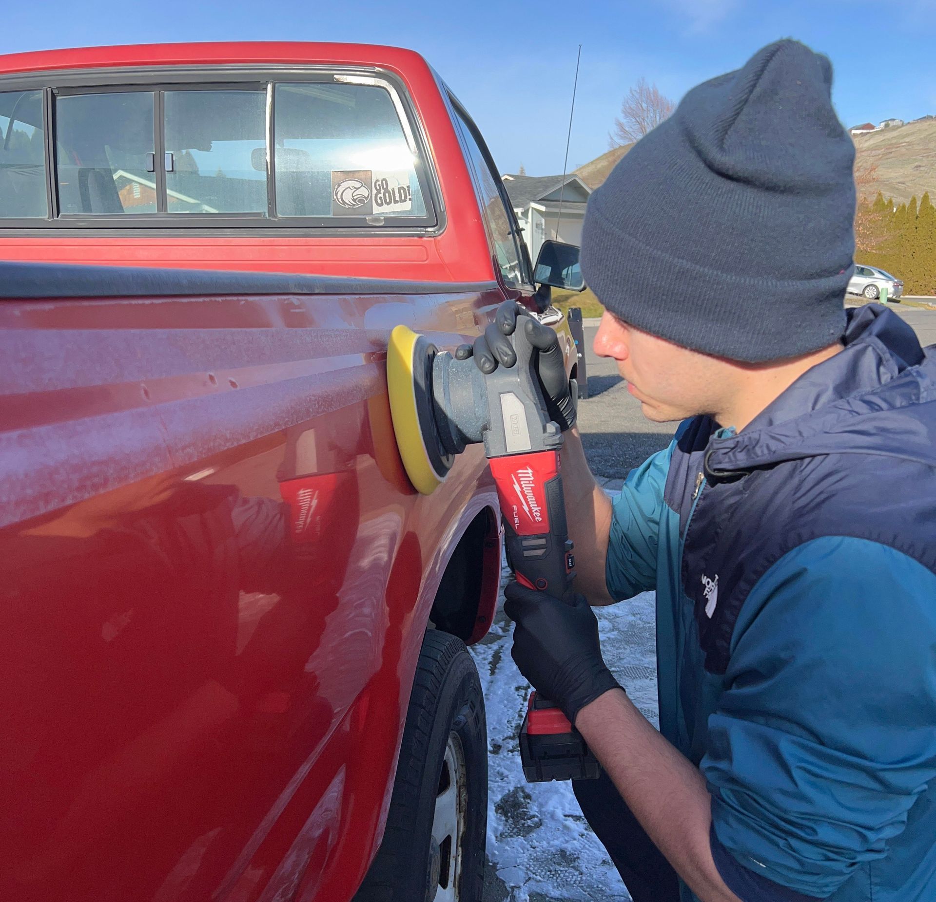 A man is polishing a red truck with a polisher