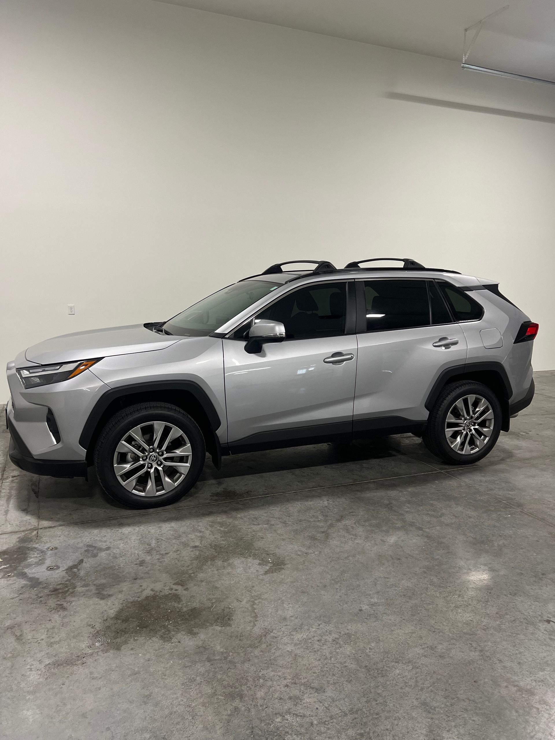 Close-up of a dark-colored car's side, showing the tinted window, side mirror, and door handle.