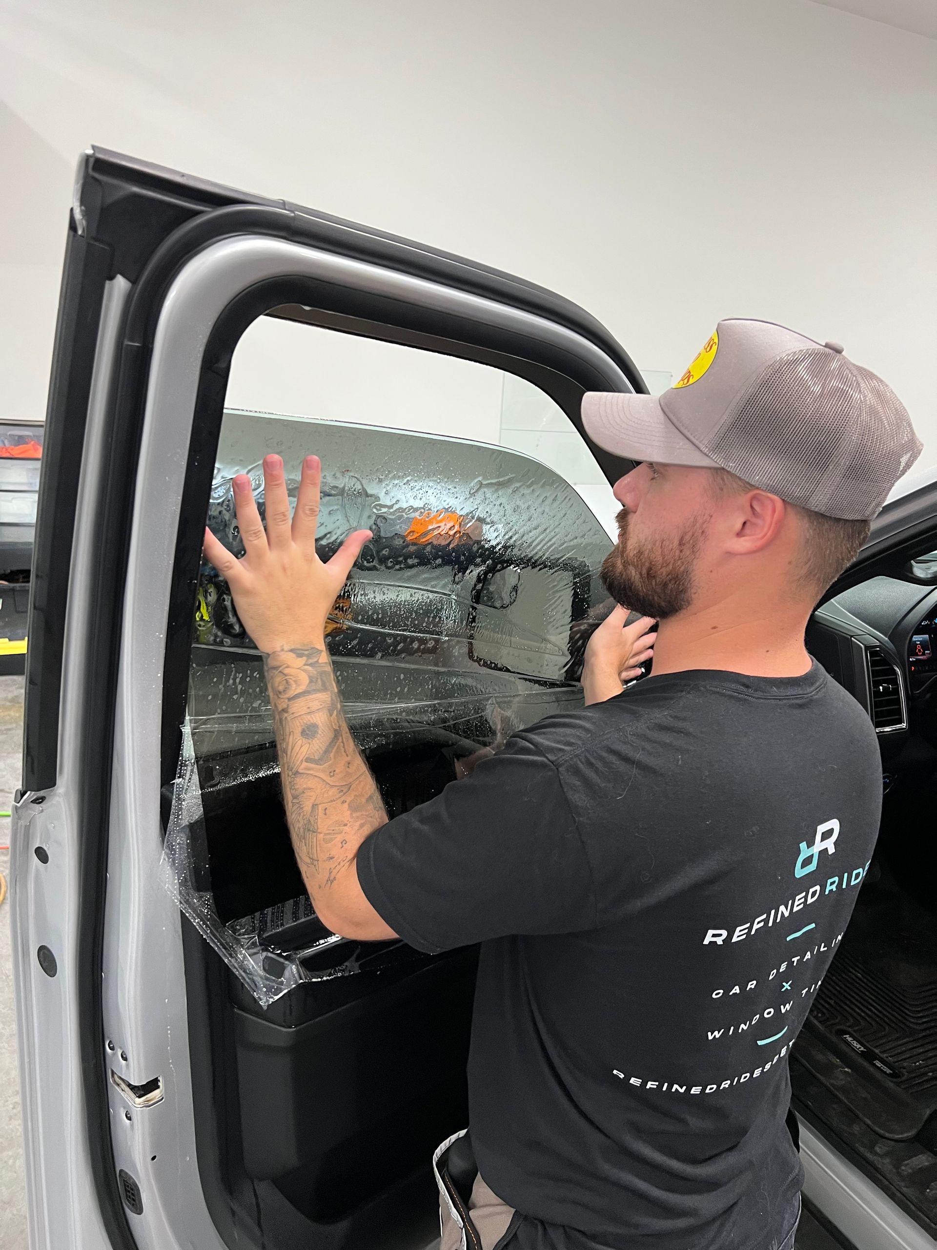 Person applying window tint to a car door indoors.