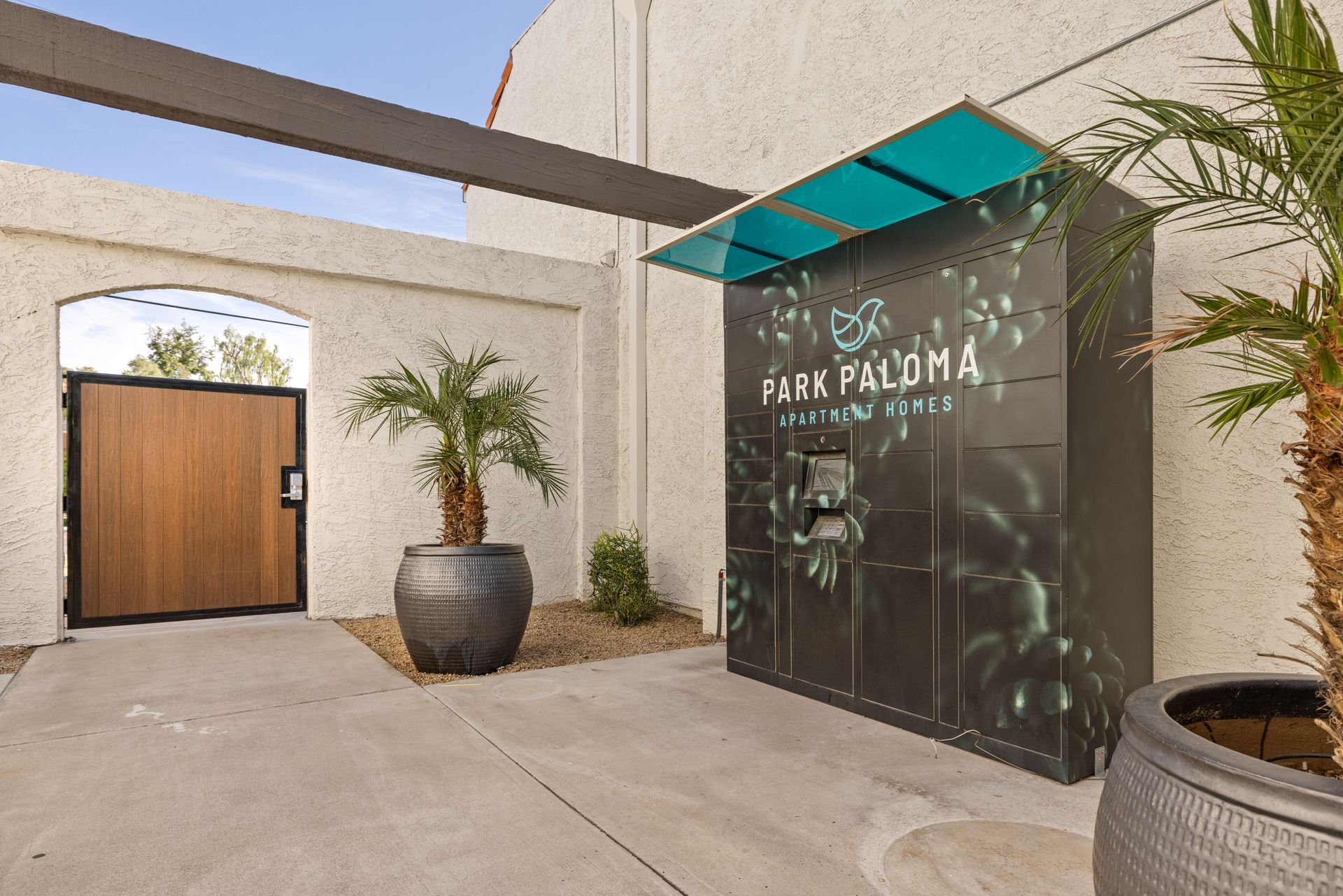 Package lockers for Park Paloma, outside a building with palm trees.