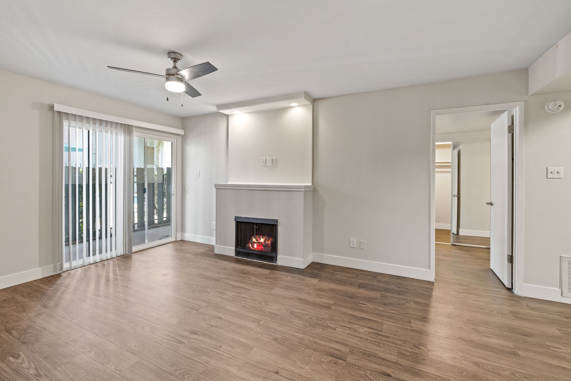 Living room with fireplace, sliding glass door to balcony, and hardwood floors.