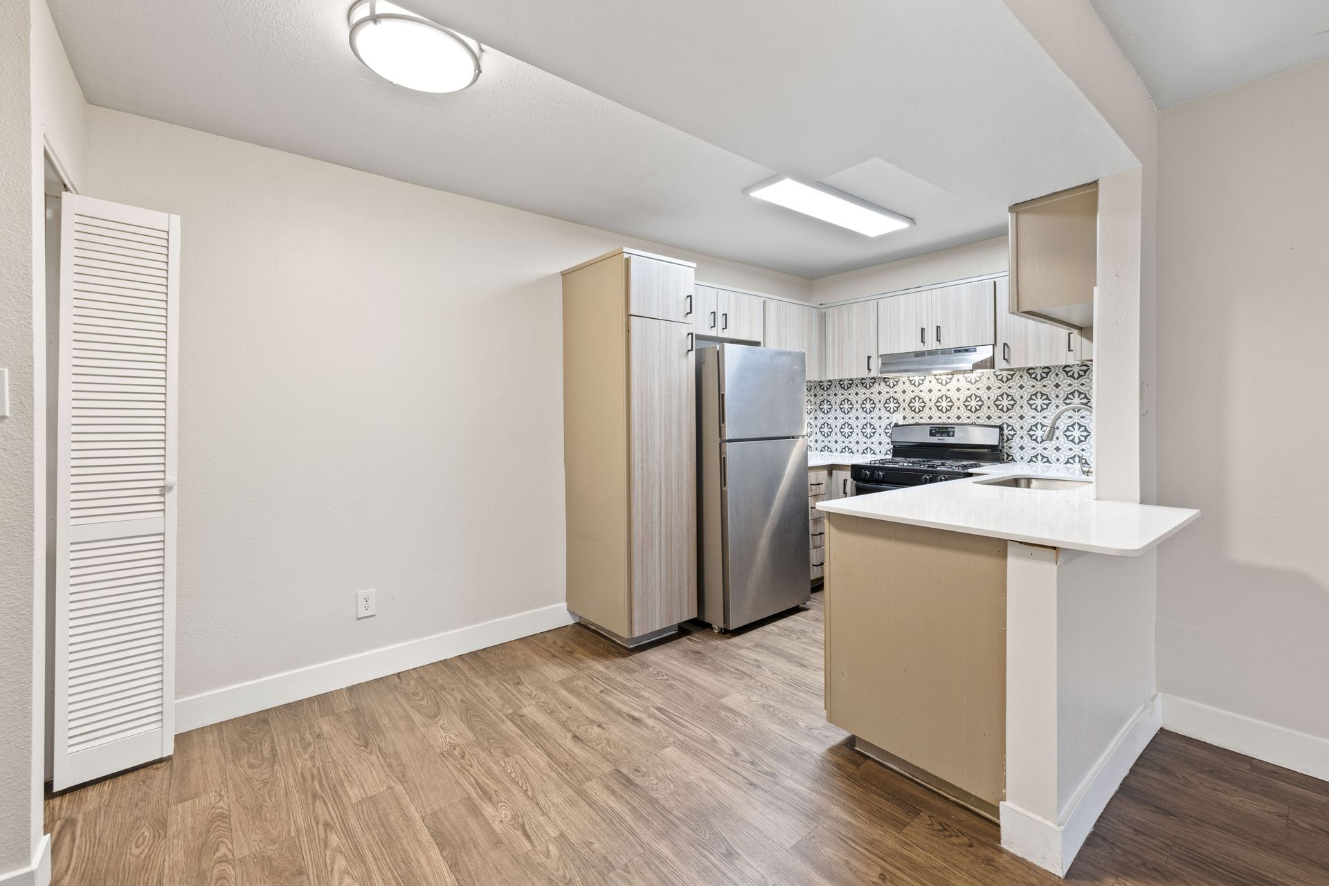Kitchen with white cabinets, stainless steel appliances, and wood-look flooring.