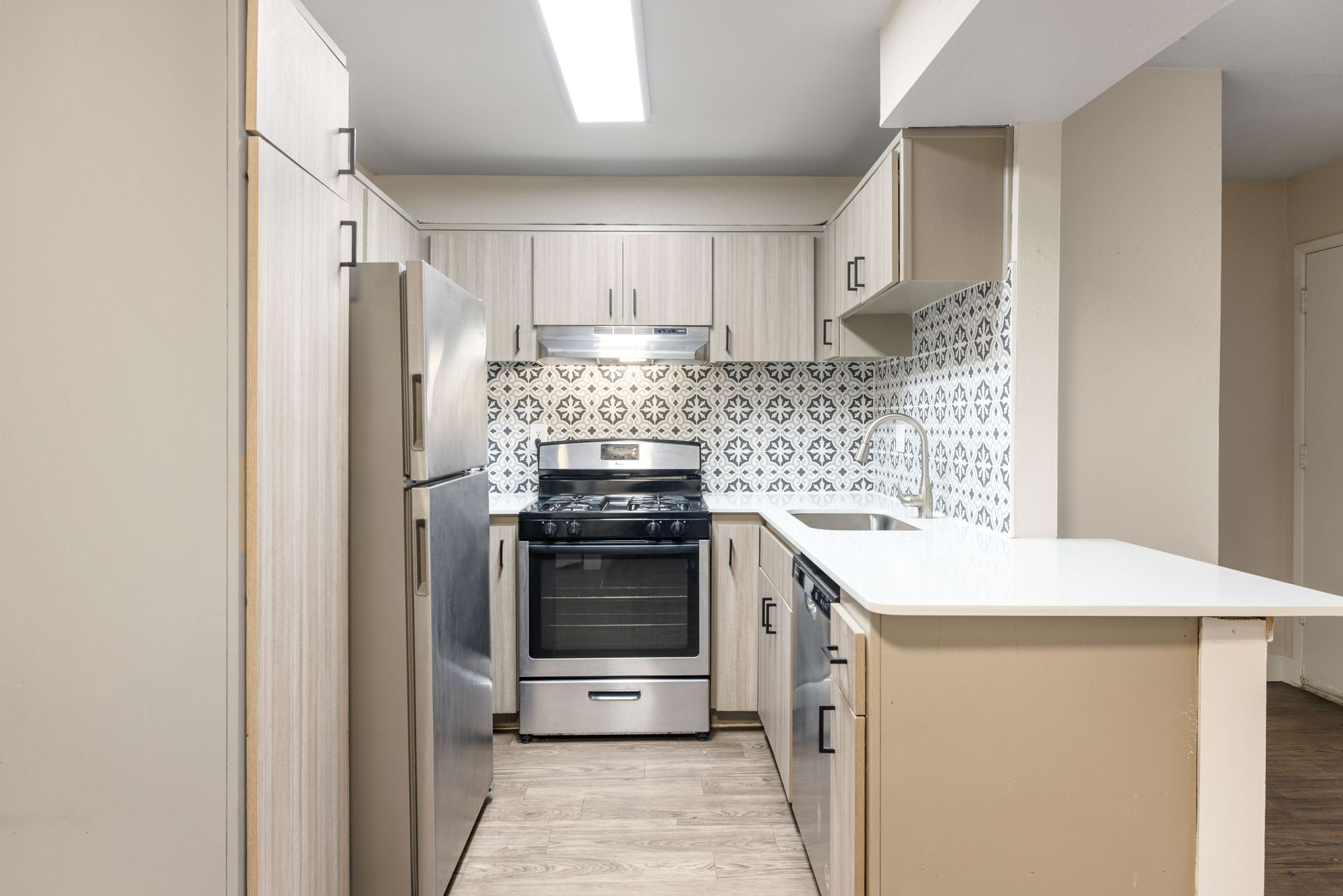 Small kitchen with light wood cabinets, stainless steel appliances, and white countertop.