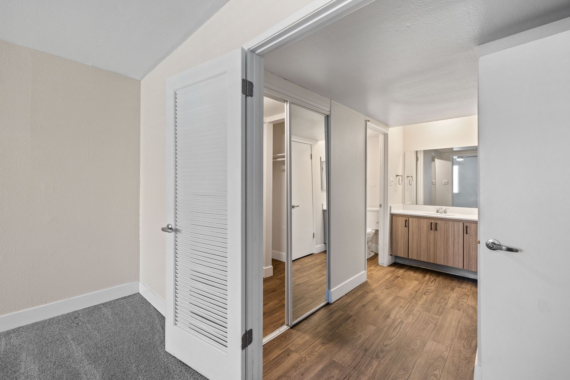 Bedroom interior with a closet and bathroom visible through open doors.