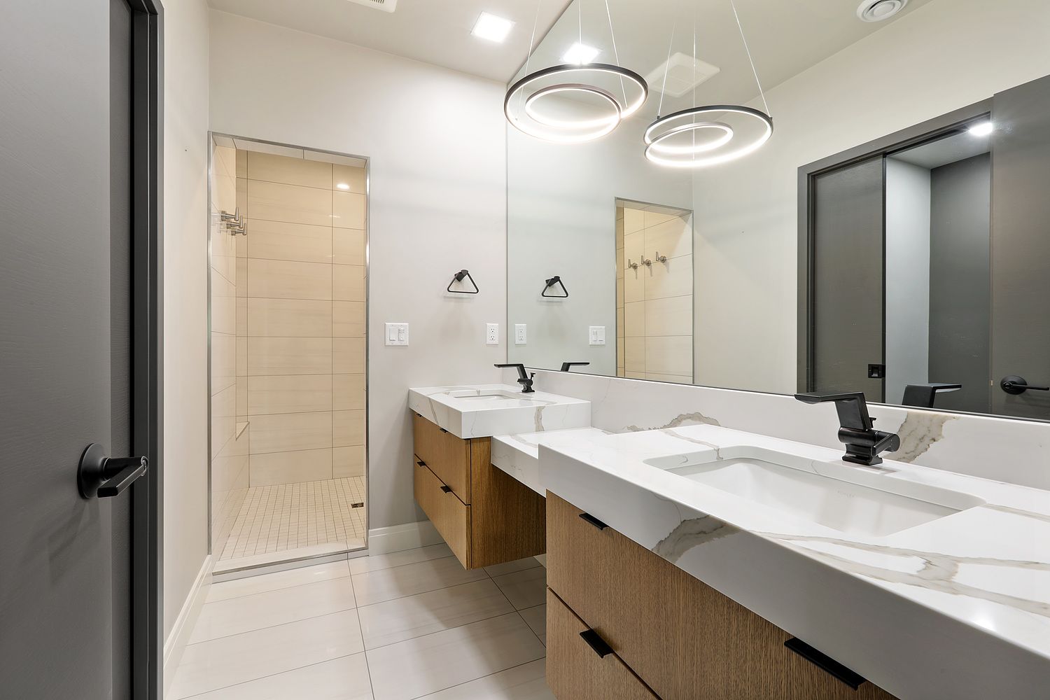 A bathroom with two sinks and a walk in shower.