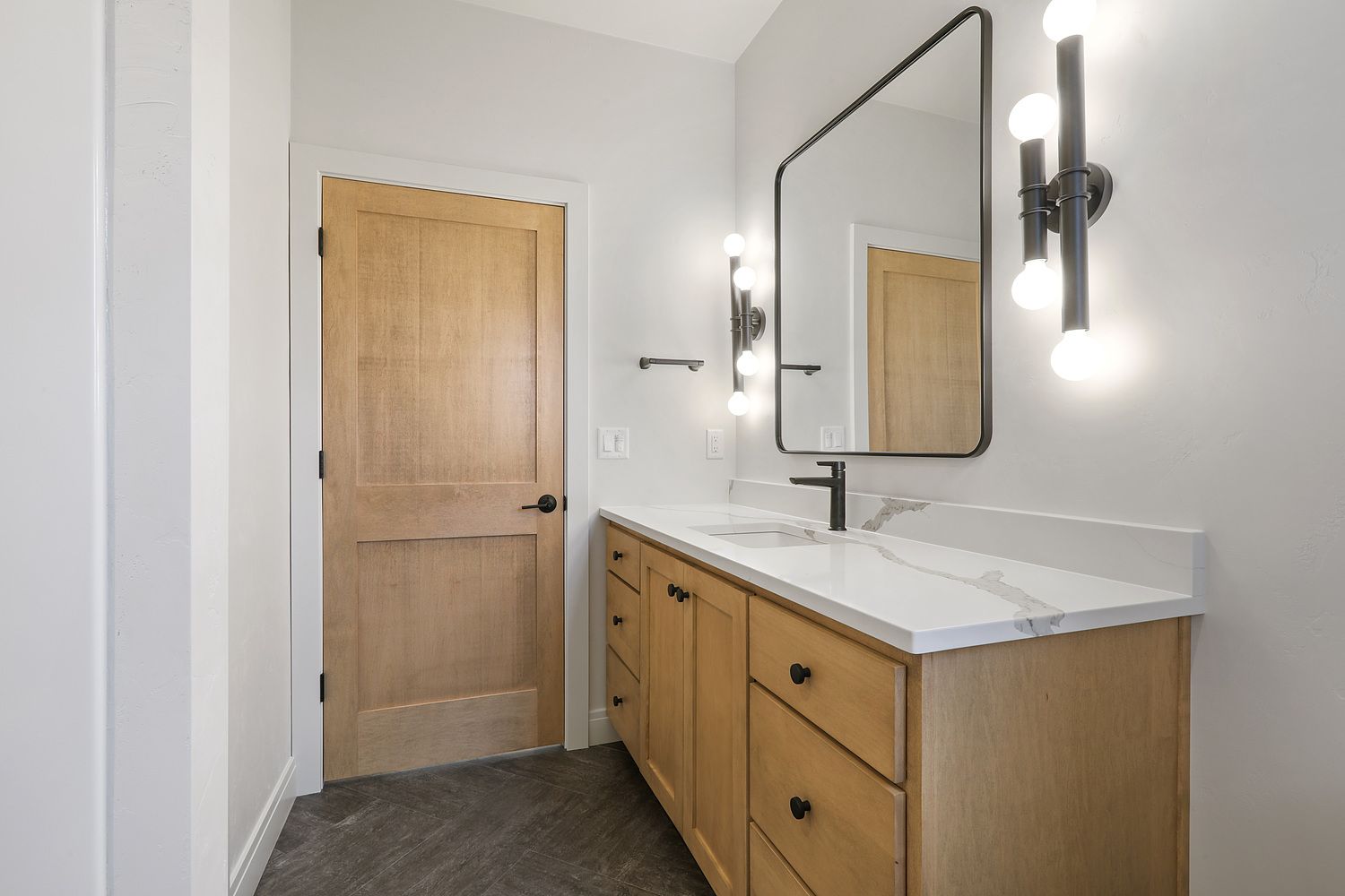 A bathroom with two sinks , a mirror and a door.
