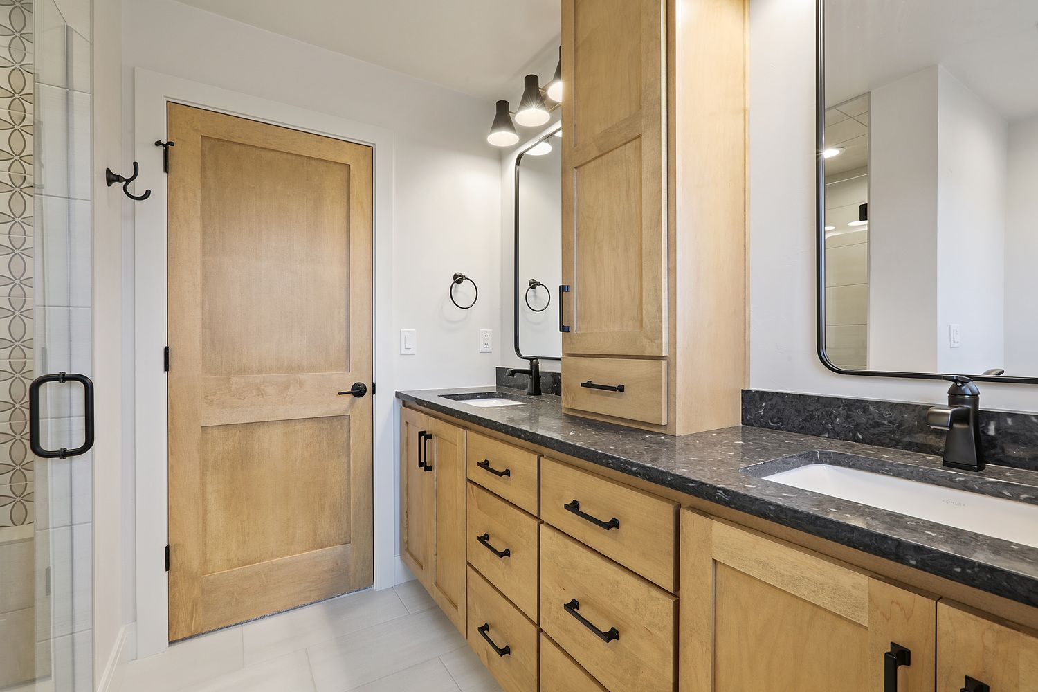 A bathroom with two sinks , a mirror and a walk in shower.