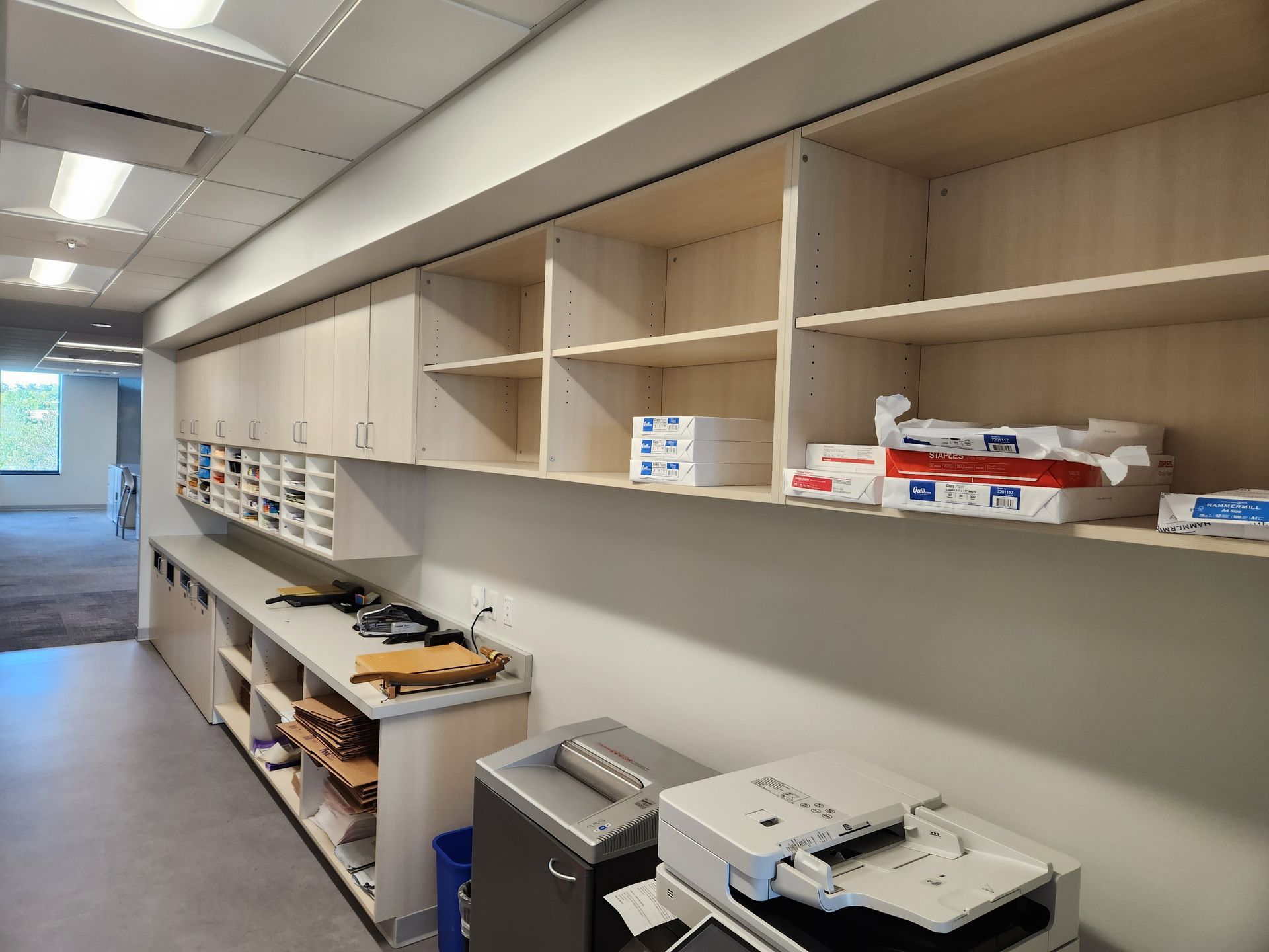 Office supply storage area with shelves and a printer.