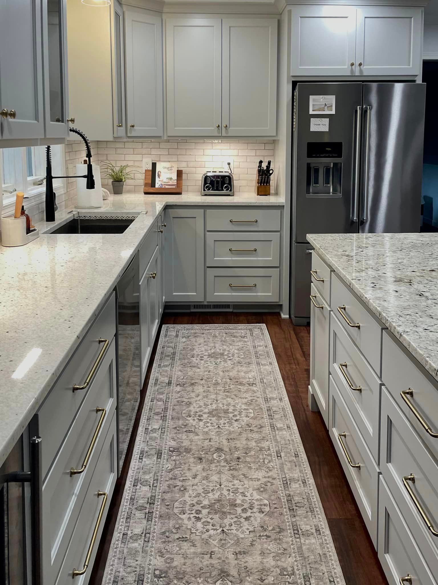 A kitchen with blue cabinets , white cabinets , stainless steel appliances and hardwood floors.