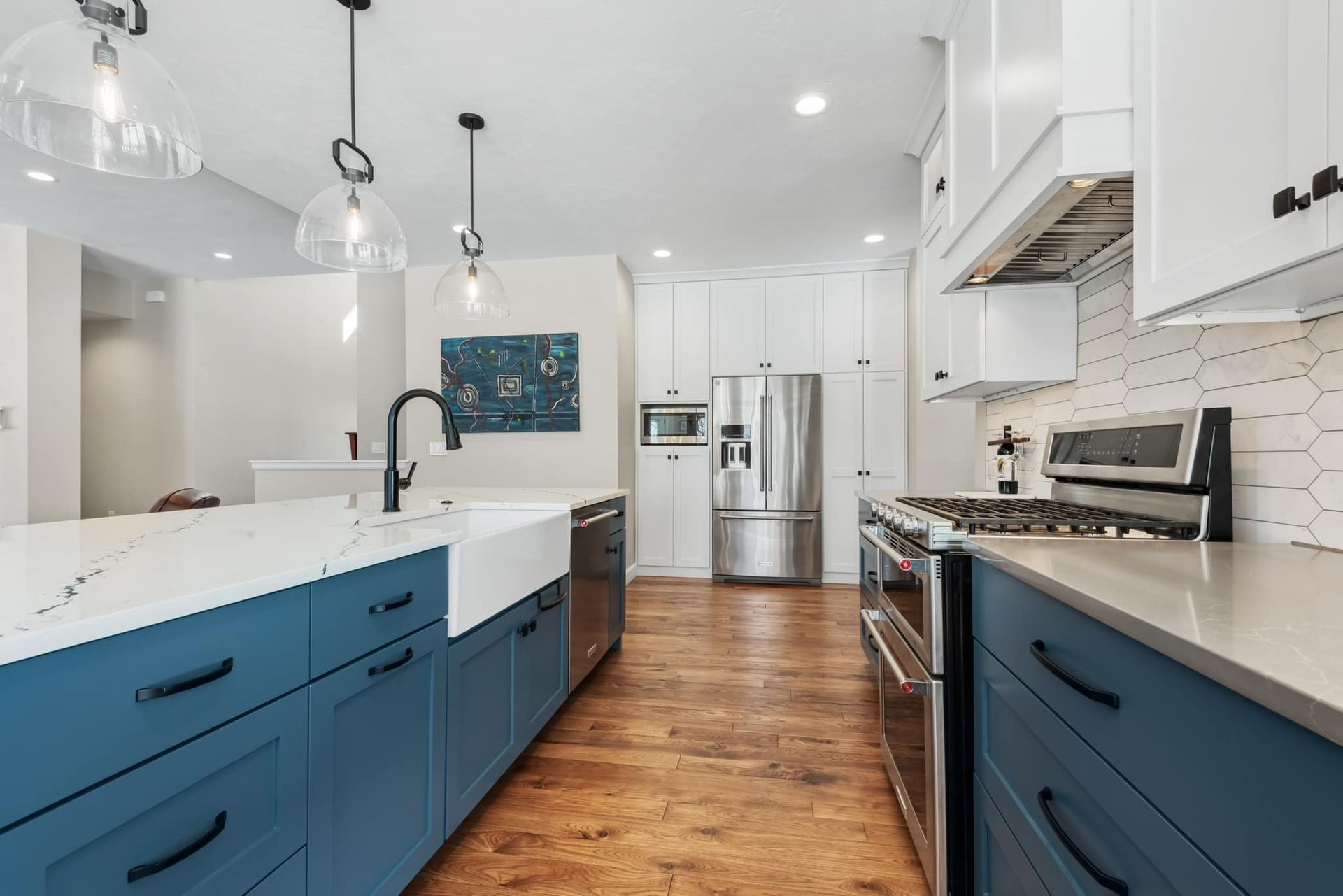 A kitchen with blue cabinets , white cabinets and stainless steel appliances.