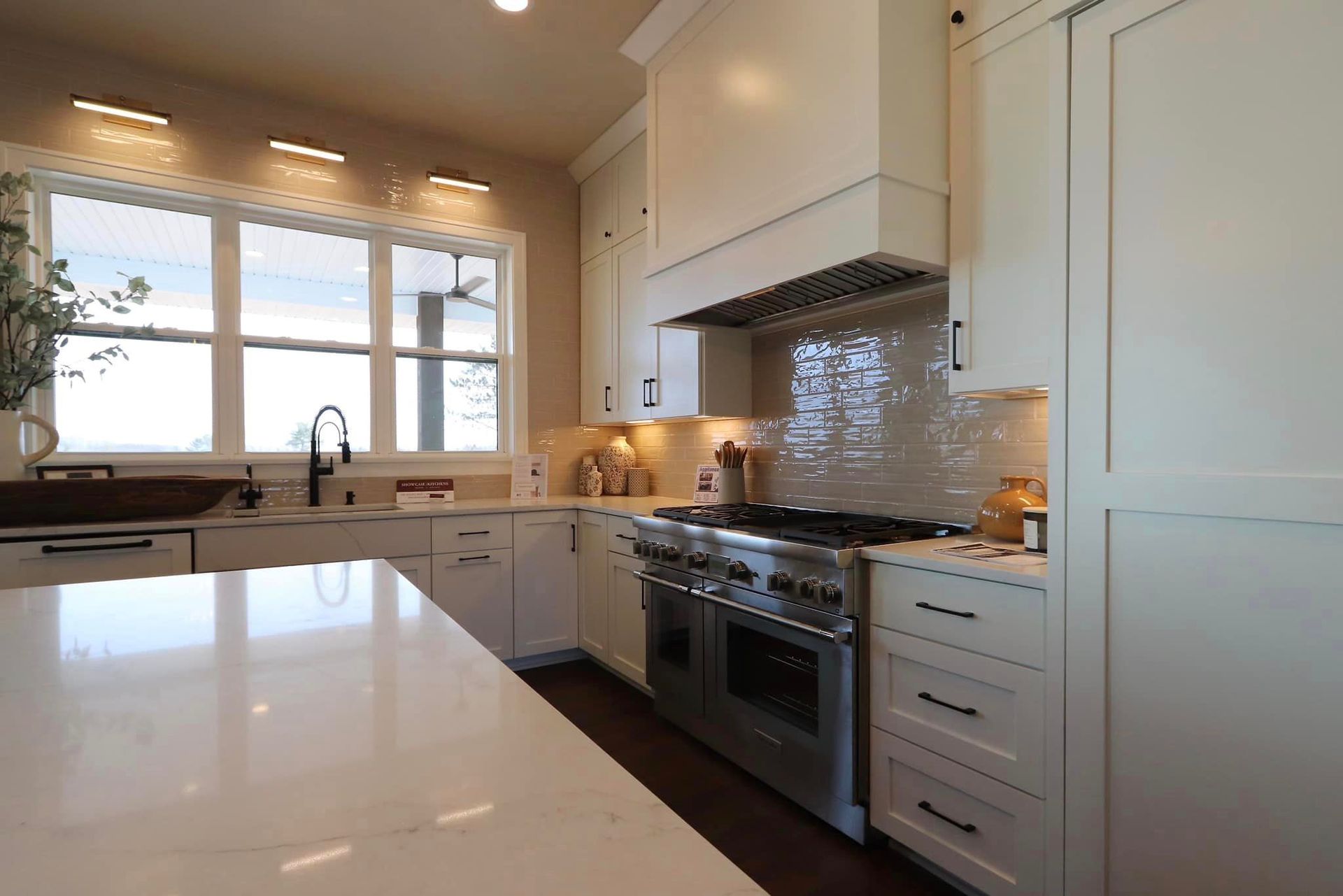 A kitchen with white cabinets , stainless steel appliances , and a large island.