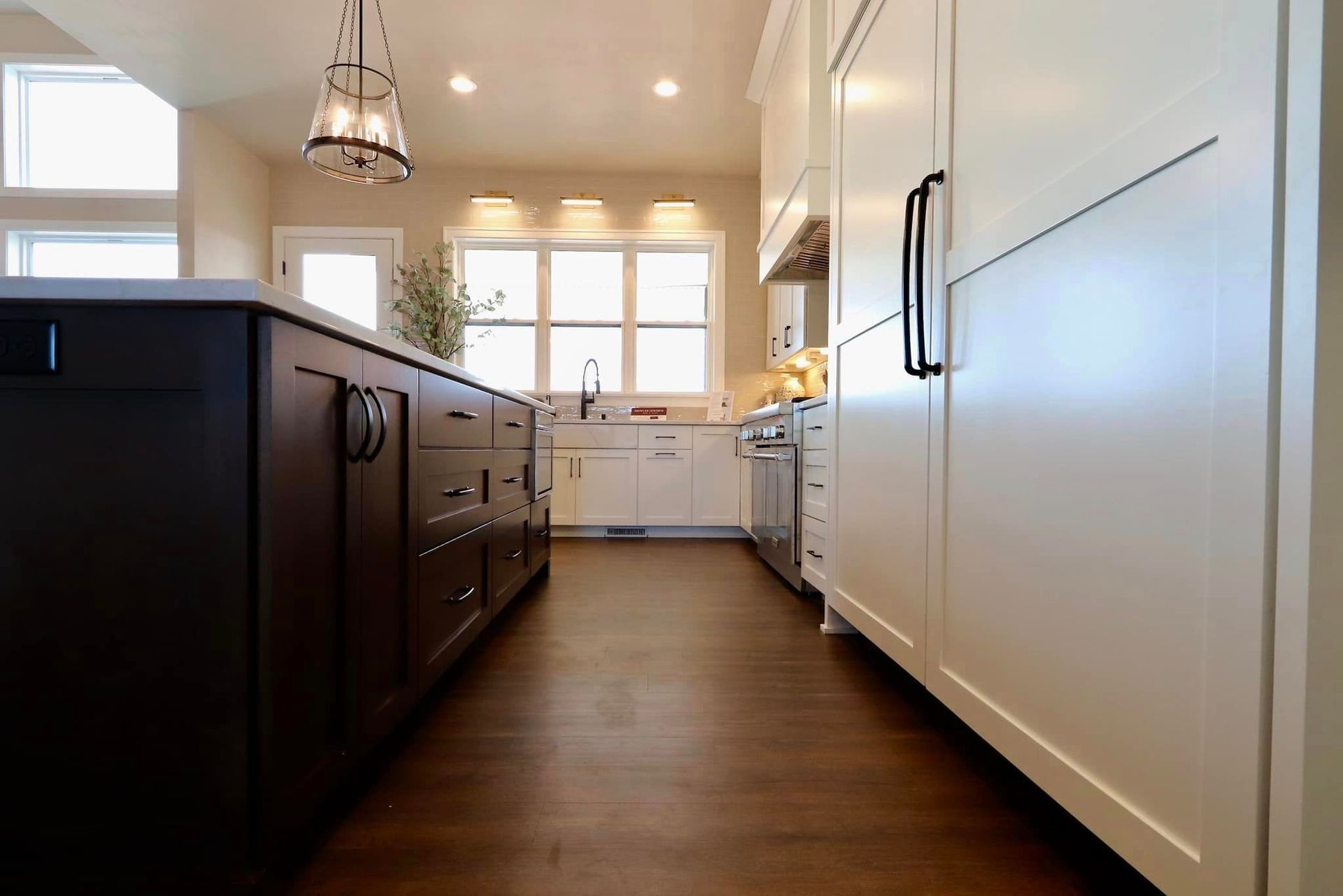 A kitchen with white cabinets and dark wood floors.