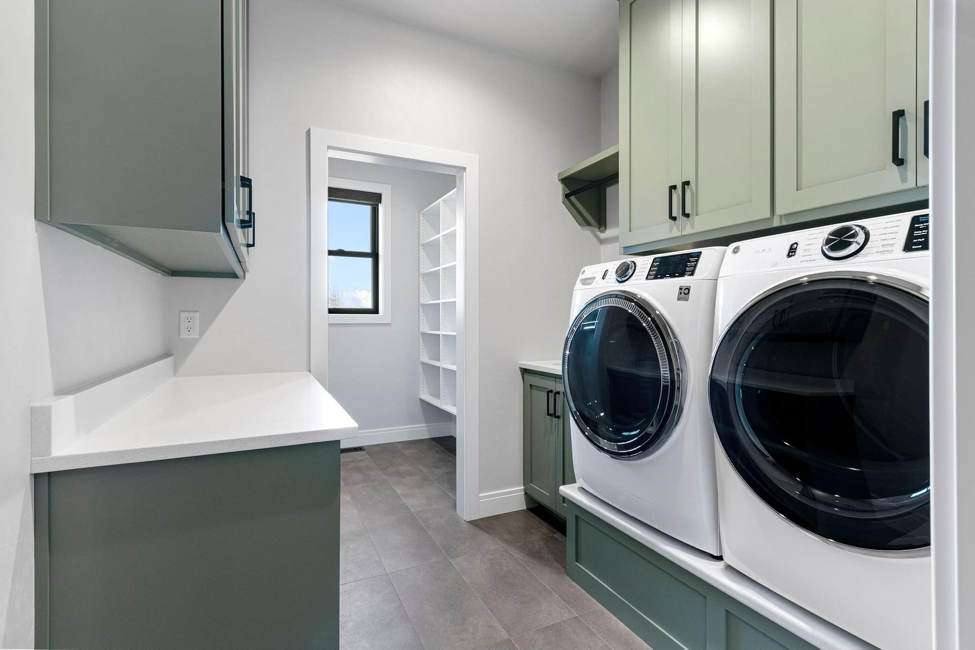 A laundry room with a washer and dryer and green cabinets.