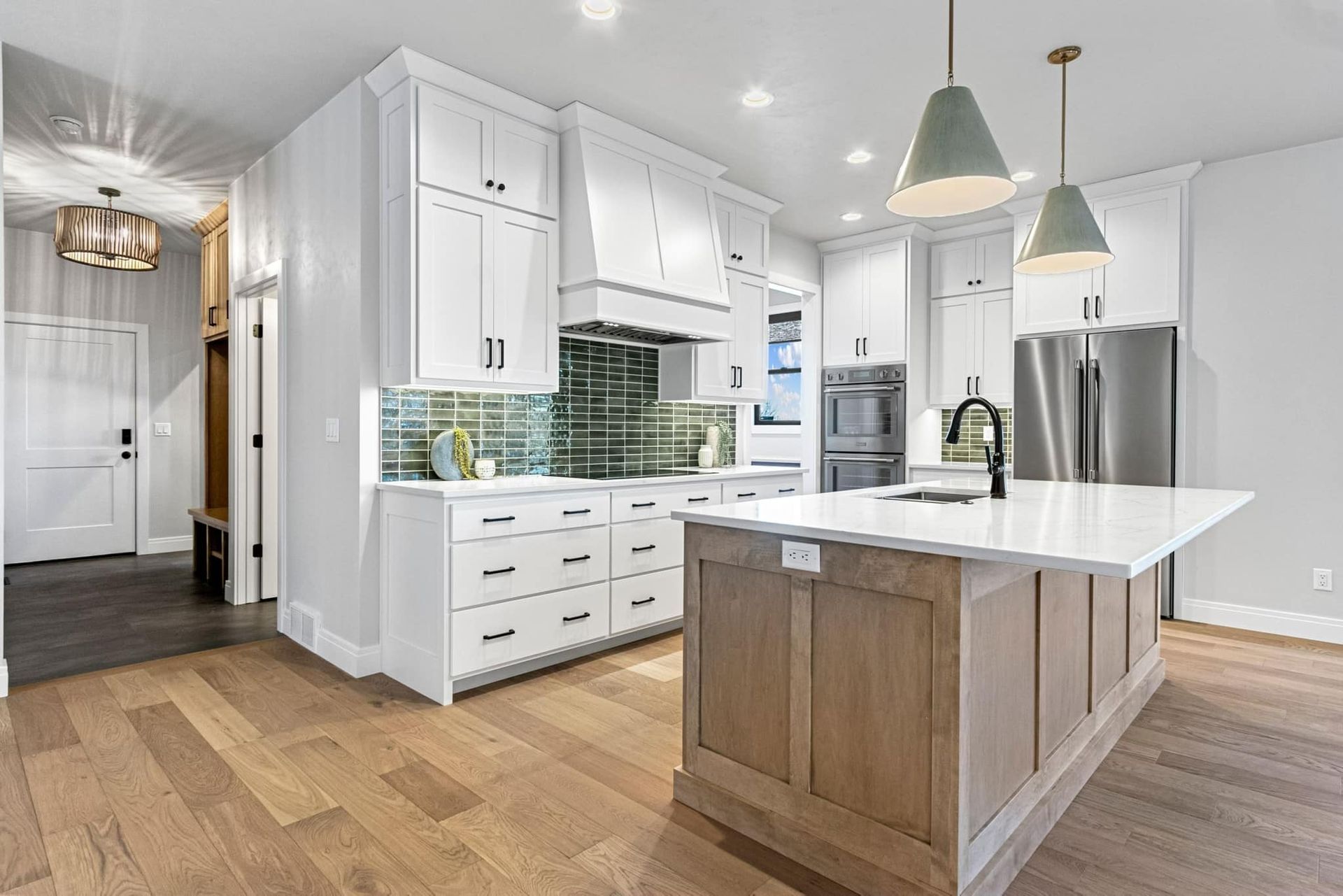 A kitchen with white cabinets , stainless steel appliances , and a large island.