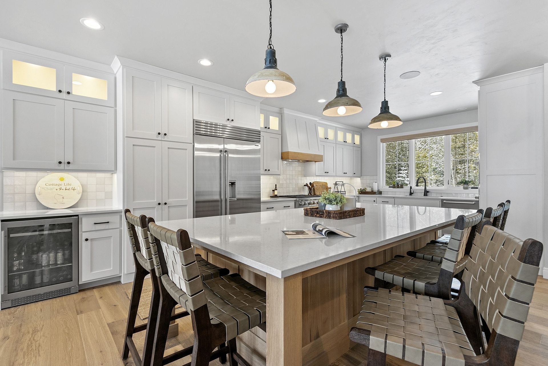 A kitchen with white cabinets , stainless steel appliances , a large island with a table and chairs.