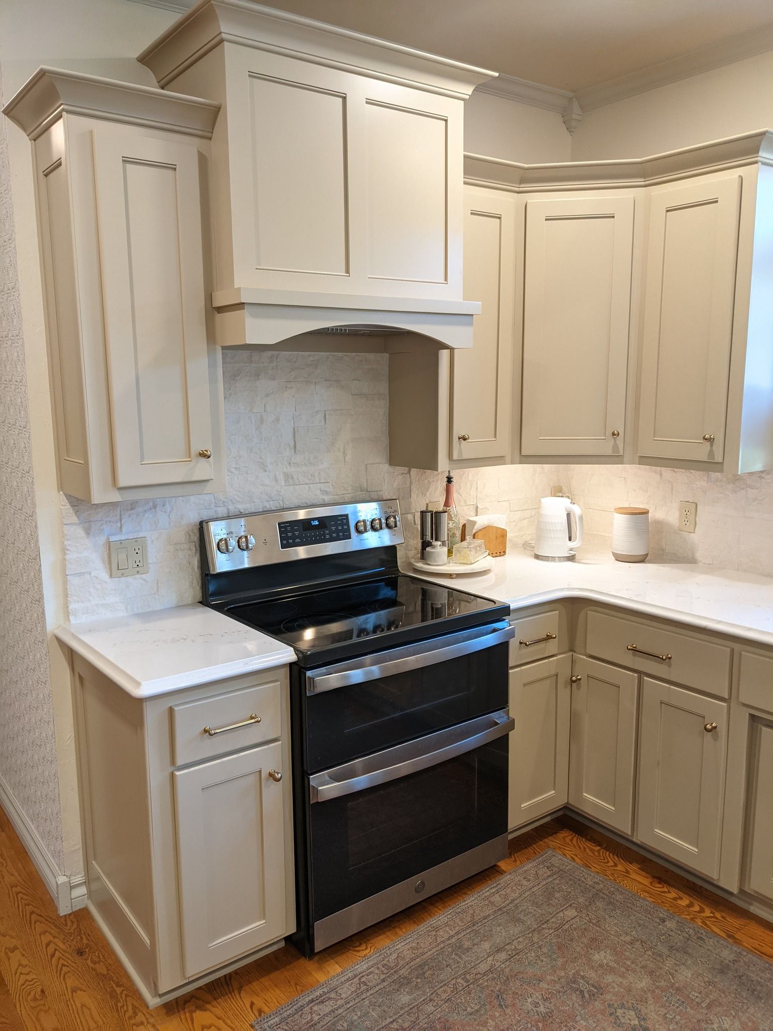 Kitchen with light-colored cabinets, stainless steel range, and white countertops.